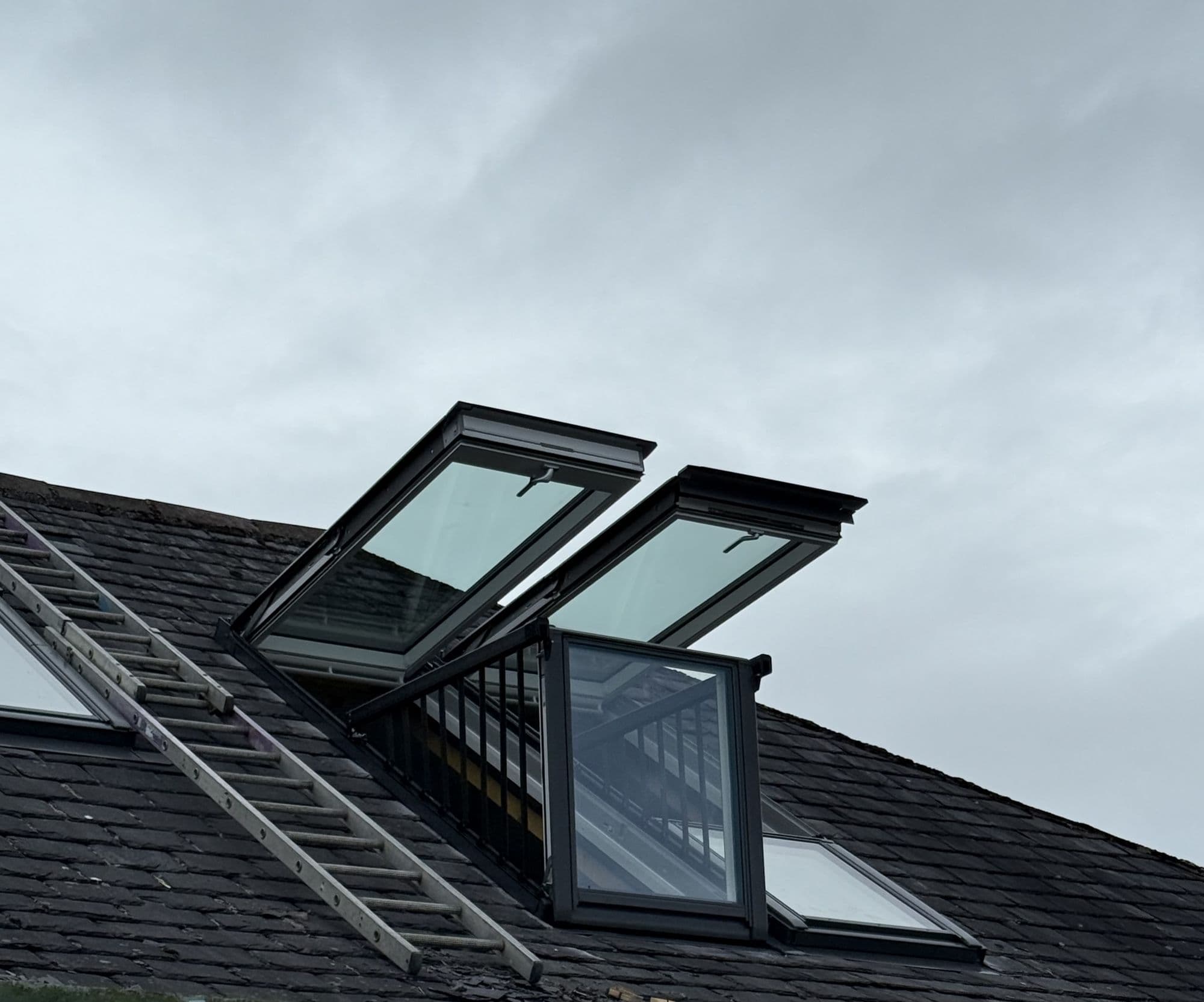Roof windows open on a dark roof, one forming a small balcony